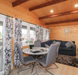 A dining area with a round table and four chairs next to a sitting area with a sofa and a coffee table at Owenbeg in Dungiven Londonderry