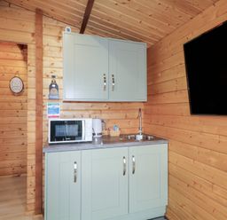 A kitchen area with a microwave kettle and sink mounted on cabinets and a wall mounted television at Owenbeg in Dungiven Londonderry
