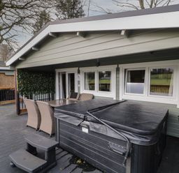 An outdoor patio with a hot tub table and chairs on a deck at The Roe in Dungiven Londonderry