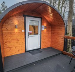 A wooden pod cabin with a white door and outdoor seating at Hawthorn in Dungiven Londonderry