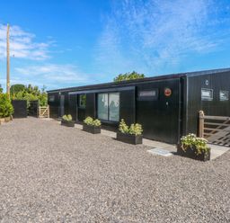 A house with a gravel driveway and planters at Y Cwt Moelfre