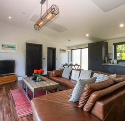 A living room with a sofa, coffee table, and TV at Y Cwt in Moelfre