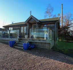 A wooden cabin with glass railing and blue flower pots at Hillview in Stottesdon near Cleobury Mortimer