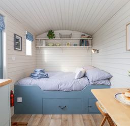 A small bedroom with a bed and shelves above at Teg in Prospidnick near Porthleven