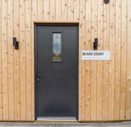 A black front door with stained glass window on a wooden paneled wall at Bears Court Barn 3 Little Rissington near Bourton-On-The-Water