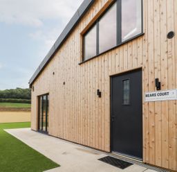 The exterior of a wooden building with black door and windows at Bears Court Barn 3 in Little Rissington near Bourton-On-The-Water
