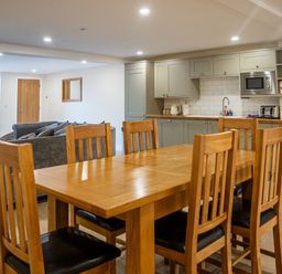 A kitchen and dining area with wooden dining table and chairs and grey cabinets at Bears Court Barn 8 Little Rissington near Bourton-On-The-Water