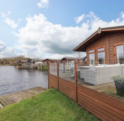 A lakefront lodge with a wooden deck and outdoor seating near Carnforth