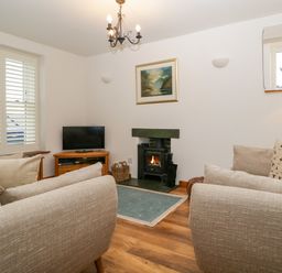 A living room with a television and fireplace at Capella Cottage in Keswick