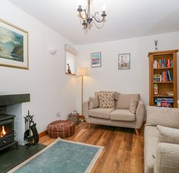 A living room with a fireplace and bookshelves at Capella Cottage in Keswick