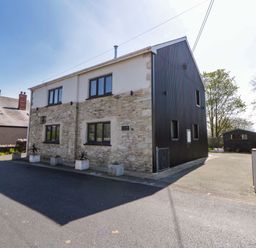A house with stone and metal facade on a street at La Bastille in Maenclochog