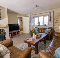 A living room with a television and leather sofas at La Bastille in Maenclochog