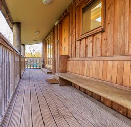 A wooden balcony with built in bench and railing at Cedrus Lodge in Skelton near Penrith