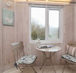 A small dining area with two chairs and a round table in a room with wooden panel walls near Hartland