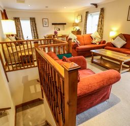 A living room with red sofas wooden coffee table and dining table with chairs at Crescent Cottage in Haltwhistle near Hadrians Wall