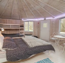 A bedroom with a double bed and bunk beds wooden walls a small table and two chairs at Spekes Mill near Hartland