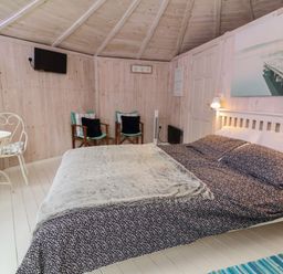 A bedroom with a bed a small round table with two chairs two armchairs and a wall-mounted TV at Spekes Mill near Hartland