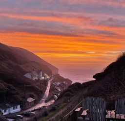 A coastal village with houses along a winding road and ocean in the background at Little Ruffo Trebarwith near Tintagel