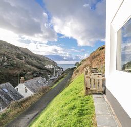 An outdoor view showing a pathway and houses near the sea at Little Ruffo in Trebarwith near Tintagel