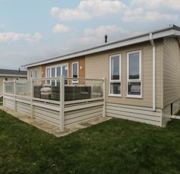 A house with a deck and grass in front at Platinum Lodge (503) Talybont
