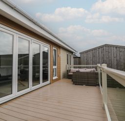 A deck area with sliding doors and outdoor furniture at Platinum Lodge (503) Talybont