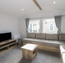 A living room with a sofa, television, and coffee table at Lido Silver Plus 111 Prestatyn