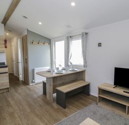 A living room with a table and bench at Lido Silver Plus 111, Prestatyn