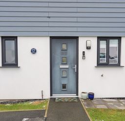 A front door with two windows and two pots outside at 19 Parc Delfryn in Benllech