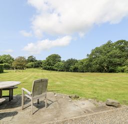 A garden with a table and chair overlooking a grassy area at Plas Pontfaen near Fishguard and Newport, Pembrokeshire