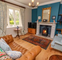 A living room with a fireplace and sofa at 9 Longhirst Village in Morpeth