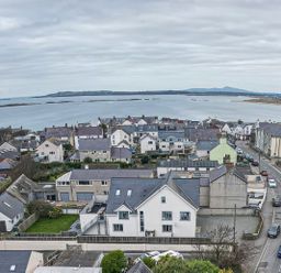 A coastal town with houses streets and parked cars overlooking a body of water at Plas Gwylan in Rhosneigr