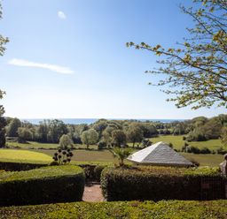 A landscape view of trees fields a small building with a tiled roof and the sea in the distance at Hunters Moon in Charlestown