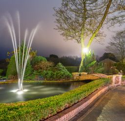 A garden with a water fountain pond a brick bridge and a lamp post at Hunters Moon in Charlestown