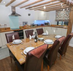 A dining table set for six in a kitchen with white cabinets and wooden countertops at Blacksmiths Cottage in Pembroke