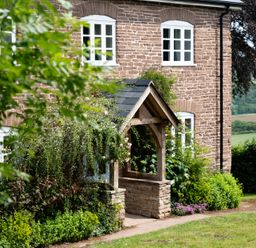 An outdoor view of a house with a garden and pathway at Henhouse Farm in Bodenham