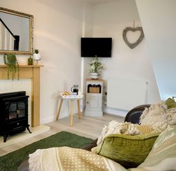 A living room with a fireplace a television and seating area at Penkenna in Crackington Haven