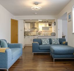 A living room with sofa and kitchen in view at Maceley Kingsbridge