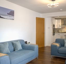 A living room with two sofas and a kitchen in the background at Maceley in Kingsbridge