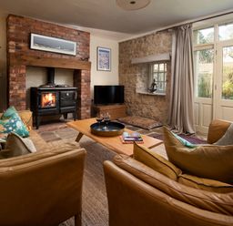 A living room with a sofa, coffee table, and wood stove at The Old Coach House Eglingham near Alnwick