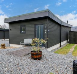 A modern black wooden building with a bench and a potted plant outside at Dundarach in Aberfeldy