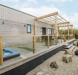 An outdoor area with a hot tub and wooden deck at Petroc in Portreath