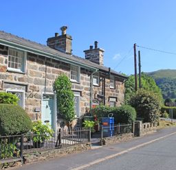 Stone cottages with gardens and a road with hills in the background at Ivy House in Beddgelert