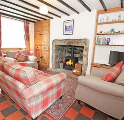 A living room with sofas around a fireplace and a TV on a shelf at Ivy House in Beddgelert