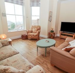 A living room with seating a television on a stand and a round coffee table at Apartment 7 Mansion House in Tenby