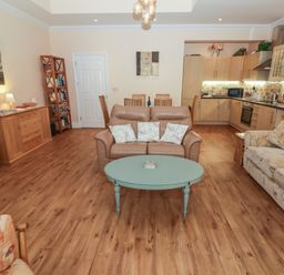 An open plan living room and kitchen with sofas a coffee table and wooden flooring at Apartment 7 Mansion House in Tenby