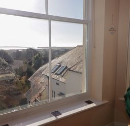 A view through a window showing rooftops and trees with sunlight coming through at Apartment 7 Mansion House in Tenby