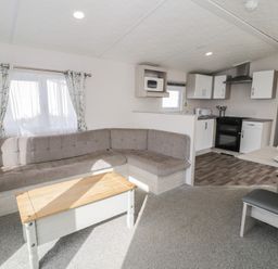 A living room with a sofa and kitchenette at Gold Caravan (316) Talybont
