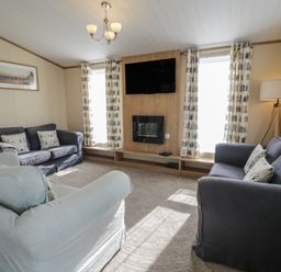 A living room with sofas, a television, and a fireplace at Gold Lodge (201) Talybont