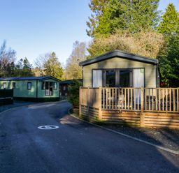 A road with mobile homes on both sides surrounded by trees at Lily Rose Lodge in White Cross Bay near Troutbeck Bridge