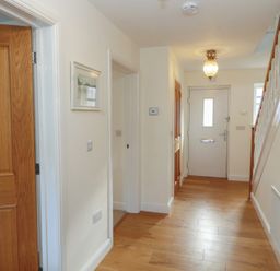 A hallway with wooden floor a white front door wooden interior doors and framed pictures on walls at 4 Centurion Rise in Penrith